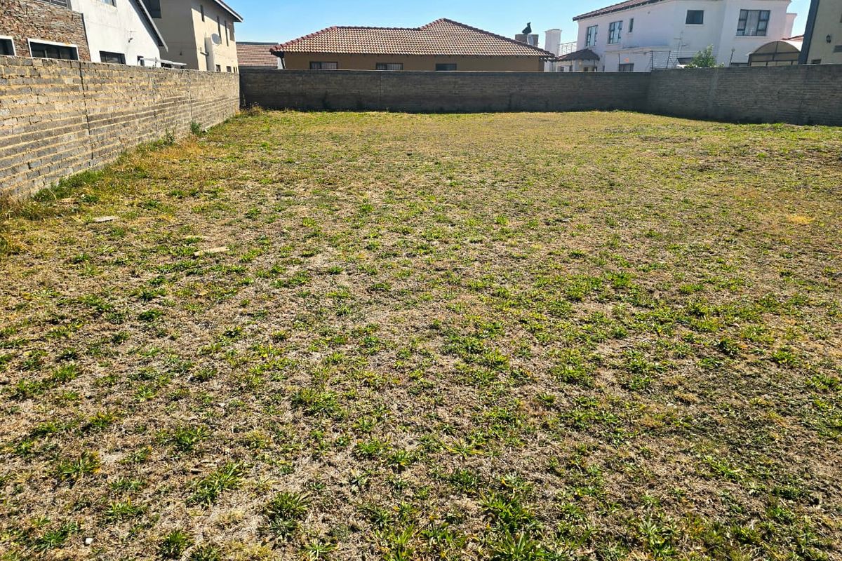 A vacant residential plot enclosed by perimeter brick walls, offering a clear space ready for development in a established neighborhood.
