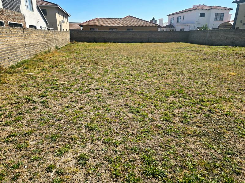 A vacant residential plot enclosed by perimeter brick walls, offering a clear space ready for development in a established neighborhood.