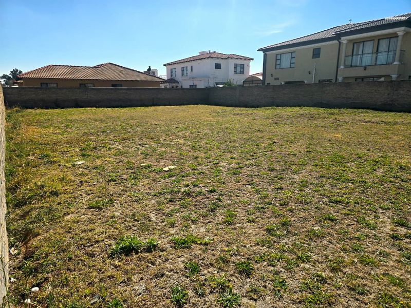 A vacant residential plot of land enclosed by a perimeter brick wall, ready for development.