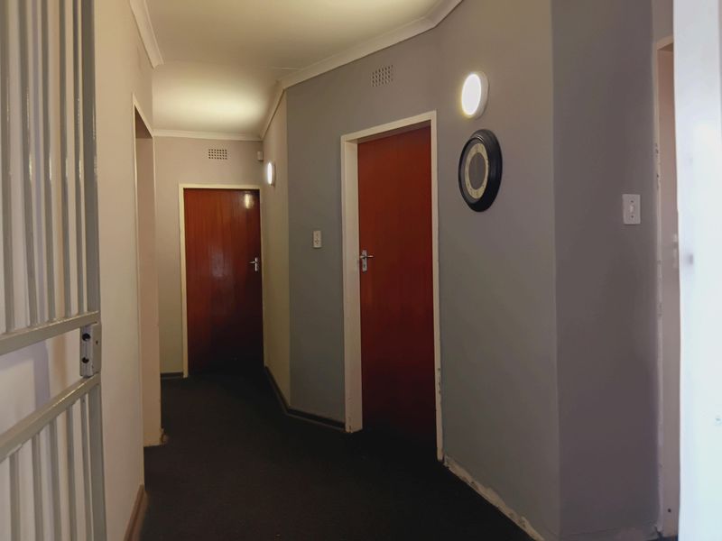 A functional hallway featuring timber doors, neutral wall paint, and overhead lighting, currently vacant and awaiting finishing touches like skirting boards.