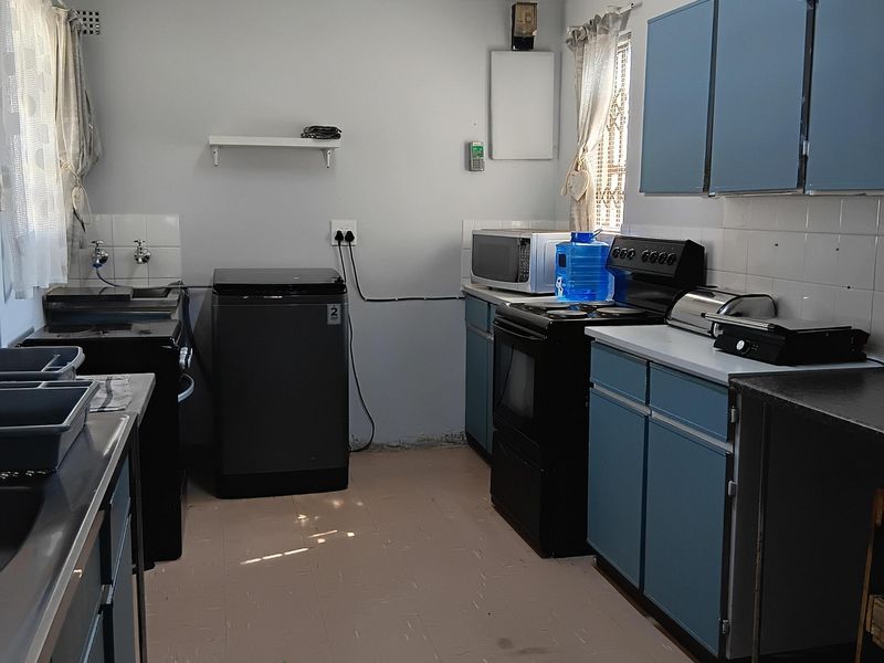 A functional kitchen featuring blue cabinetry, tiled splashbacks, and a freestanding stove, offering a practical layout with potential for modern updates.