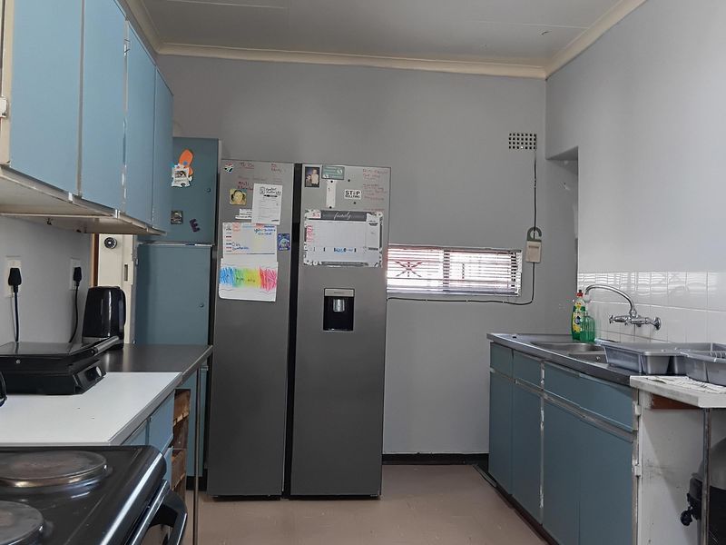 A functional kitchen featuring blue cabinetry, a stainless steel sink, and an electric stove, offering a dated aesthetic with potential for modernization.