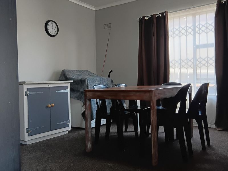 A dining area featuring carpet flooring, a ceiling light fixture, and a window fitted with a security gate.