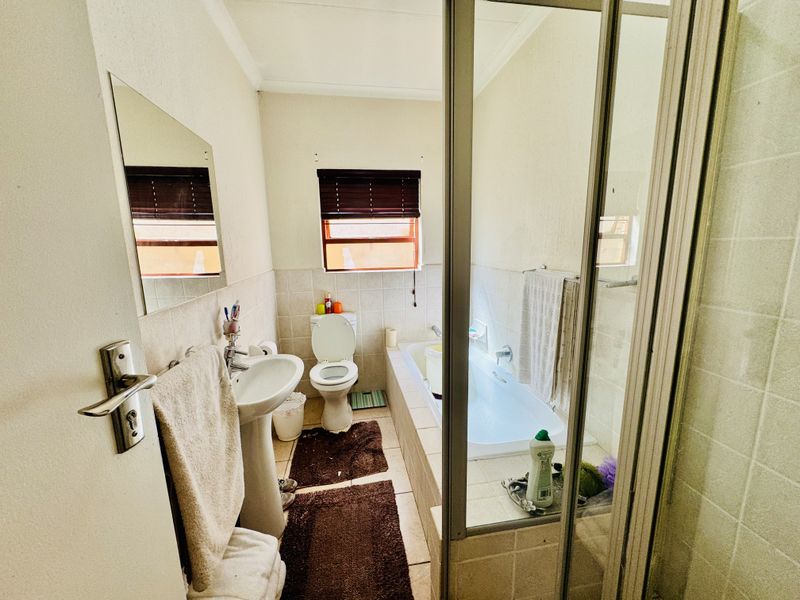 A functional bathroom featuring a pedestal basin, toilet, built-in bathtub, and a separate shower enclosure with tiled finishes.
