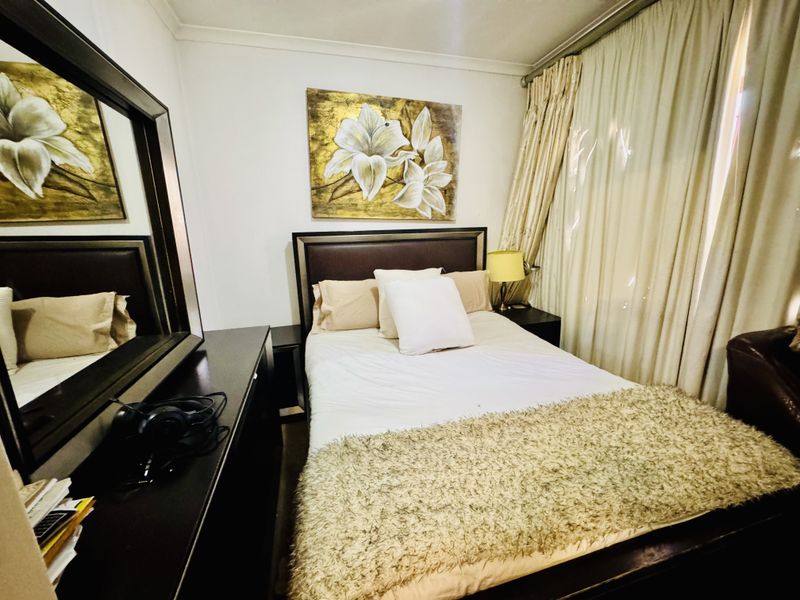 A compact bedroom featuring neutral walls, coving, and floor-to-ceiling curtains.