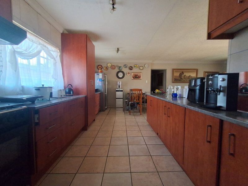 A functional kitchen featuring wood-look laminate cabinetry, tiled flooring, and ample counter space, offering a practical layout for daily meal preparation.