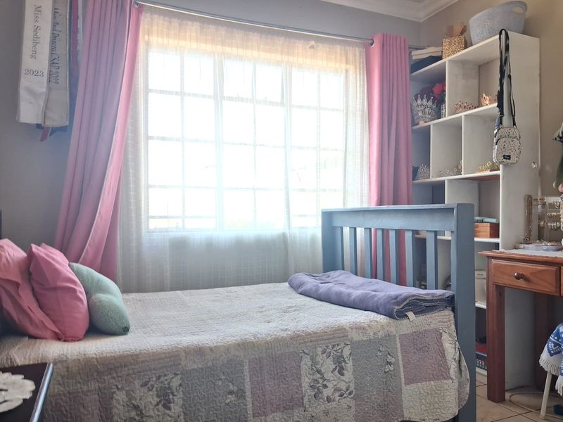 A cozy bedroom featuring a large grid-pattern window and a built-in shelving unit, providing functional storage and natural light.