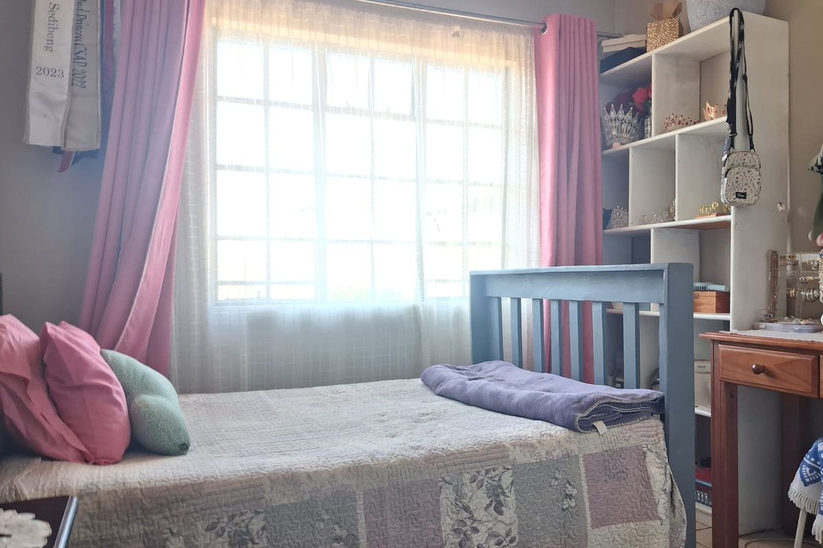 A cozy bedroom featuring a large grid-pattern window and a built-in shelving unit, providing functional storage and natural light.