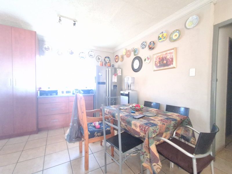Open-plan kitchen and dining area featuring tiled flooring, built-in cabinetry, and coved ceiling cornices.
