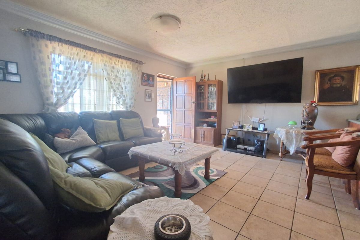 A living room featuring tiled flooring, cornicing, and a ceiling-mounted light fixture, providing a functional space with direct access to an exterior area.