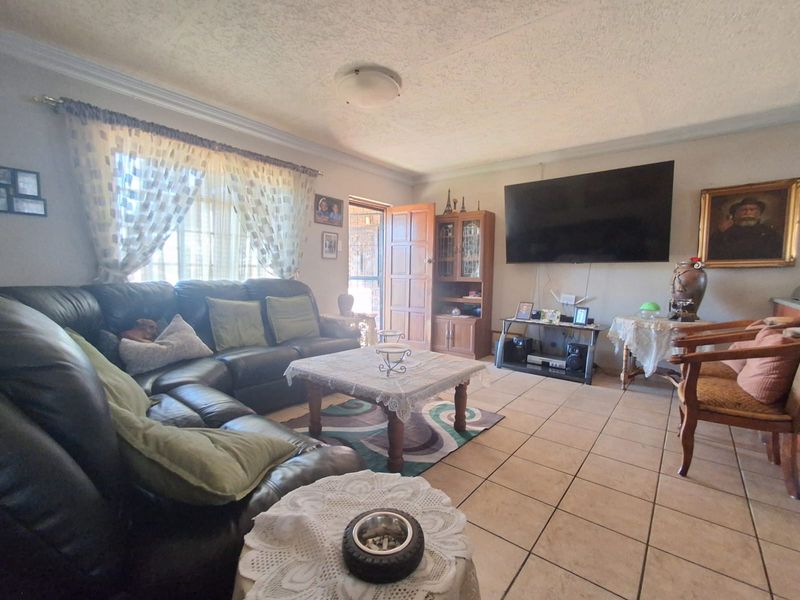 A living room featuring tiled flooring, cornicing, and a ceiling-mounted light fixture, providing a functional space with direct access to an exterior area.