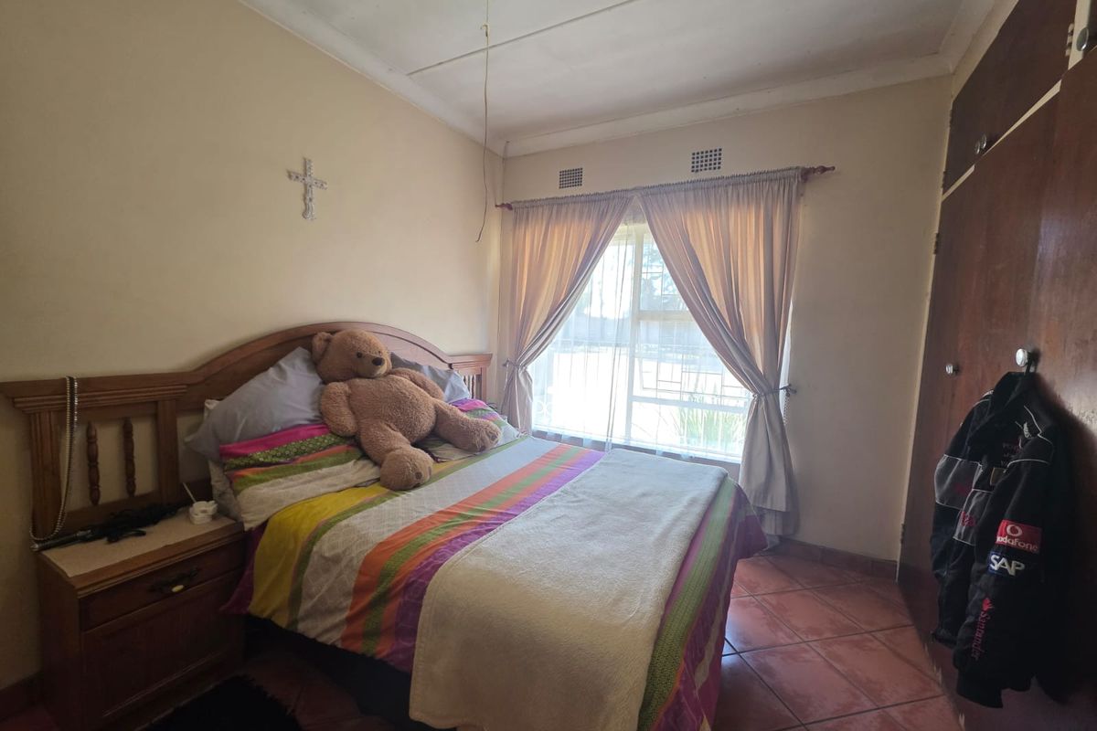 A functional bedroom featuring tiled flooring, built-in cupboards, and a ceiling fan, offering a comfortable and practical living space.