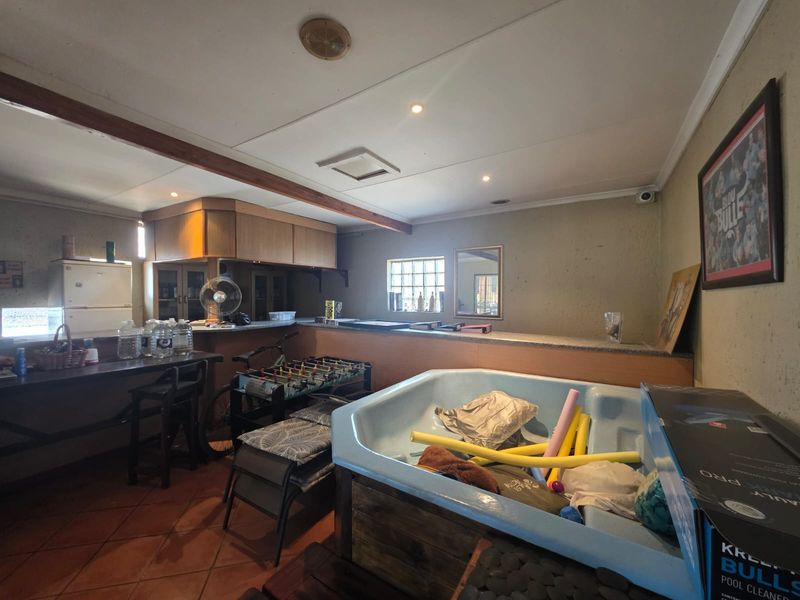 A spacious indoor bar area featuring a built-in counter, tiled flooring, and recessed lighting, offering potential for a modern entertainment space renovation.