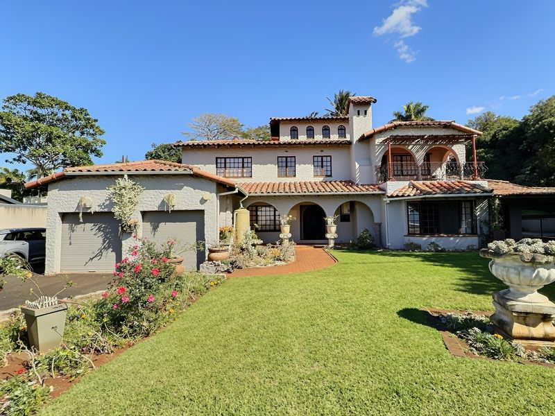 A well-maintained Mediterranean-style residence featuring a terracotta tiled roof, double garage, arched entrance, and an upper-level balcony overlooking a manicured front garden.