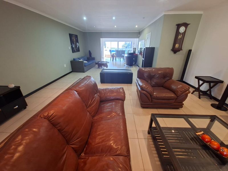 Spacious open-plan living area featuring neutral tiled flooring, recessed lighting, and large sliding doors providing access to the outdoor space.