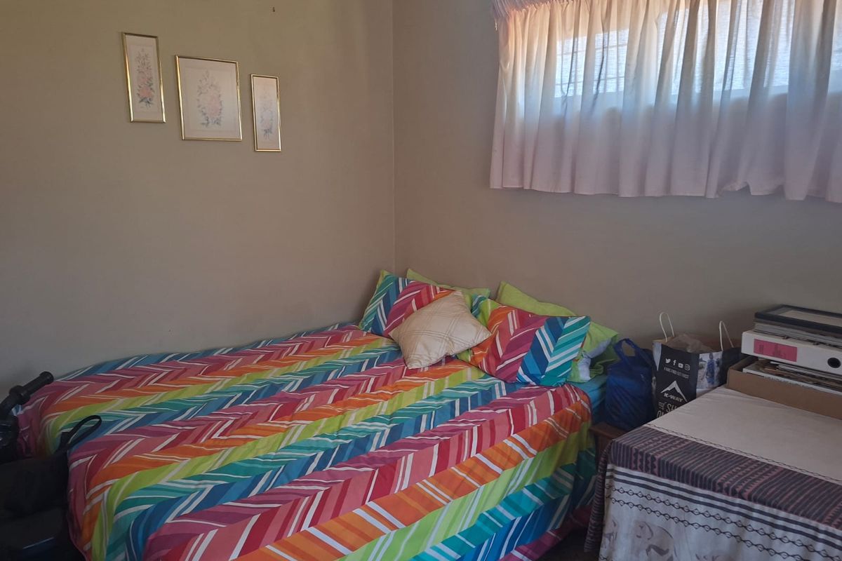 A standard bedroom featuring neutral wall finishes and a window with installed curtain rails.