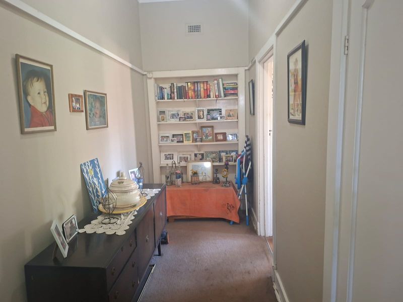 A functional hallway featuring built-in shelving and traditional picture rails, providing a practical transition space within the home.