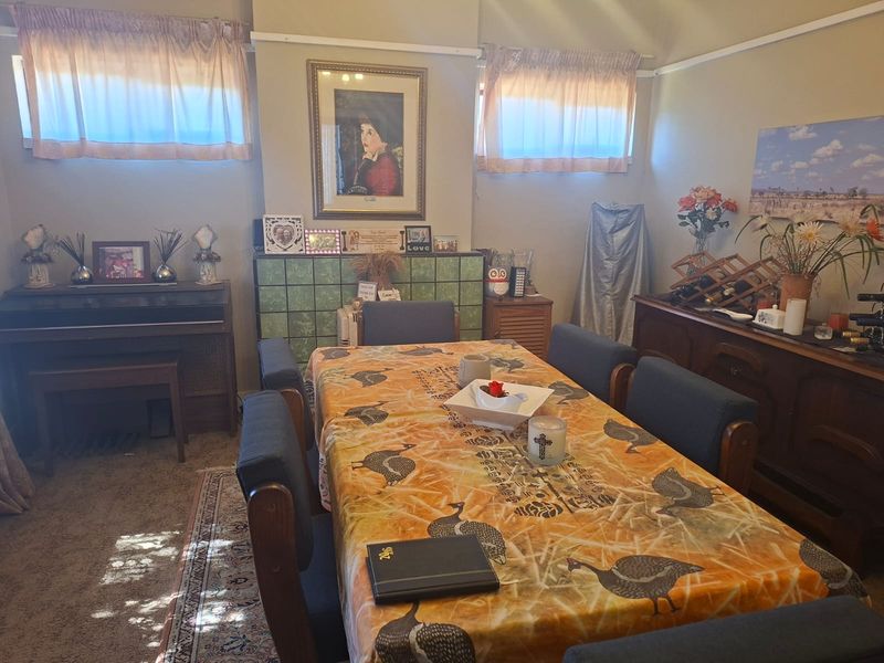 A traditional dining room featuring a tiled fireplace surround, picture rails, and carpeted flooring, offering a classic layout for family meals.