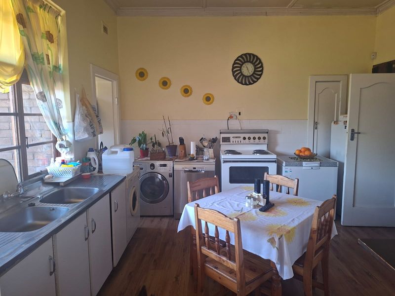A functional kitchen featuring a double bowl sink, built-in cabinetry, and a freestanding stove, with laminate flooring and a tiled splashback.