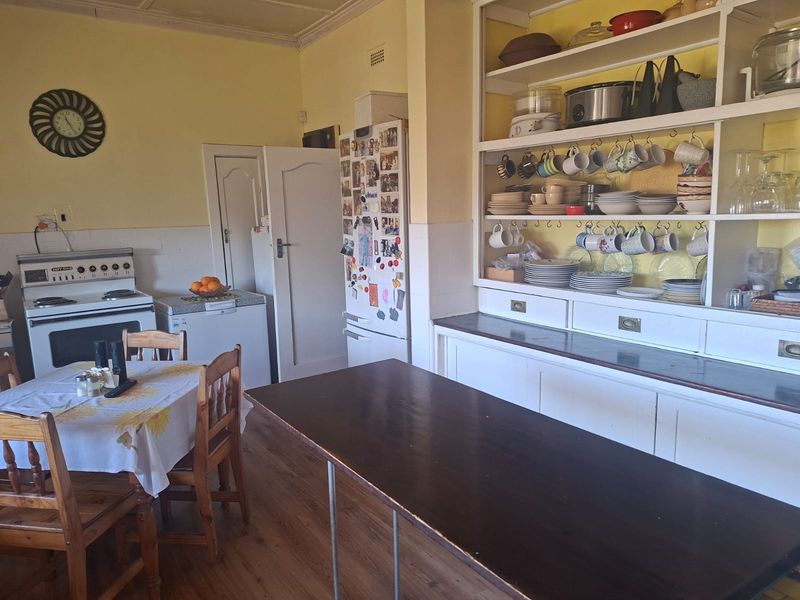 A dated kitchen featuring a freestanding stove, built-in open shelving, and laminate flooring, offering significant potential for a modern renovation.