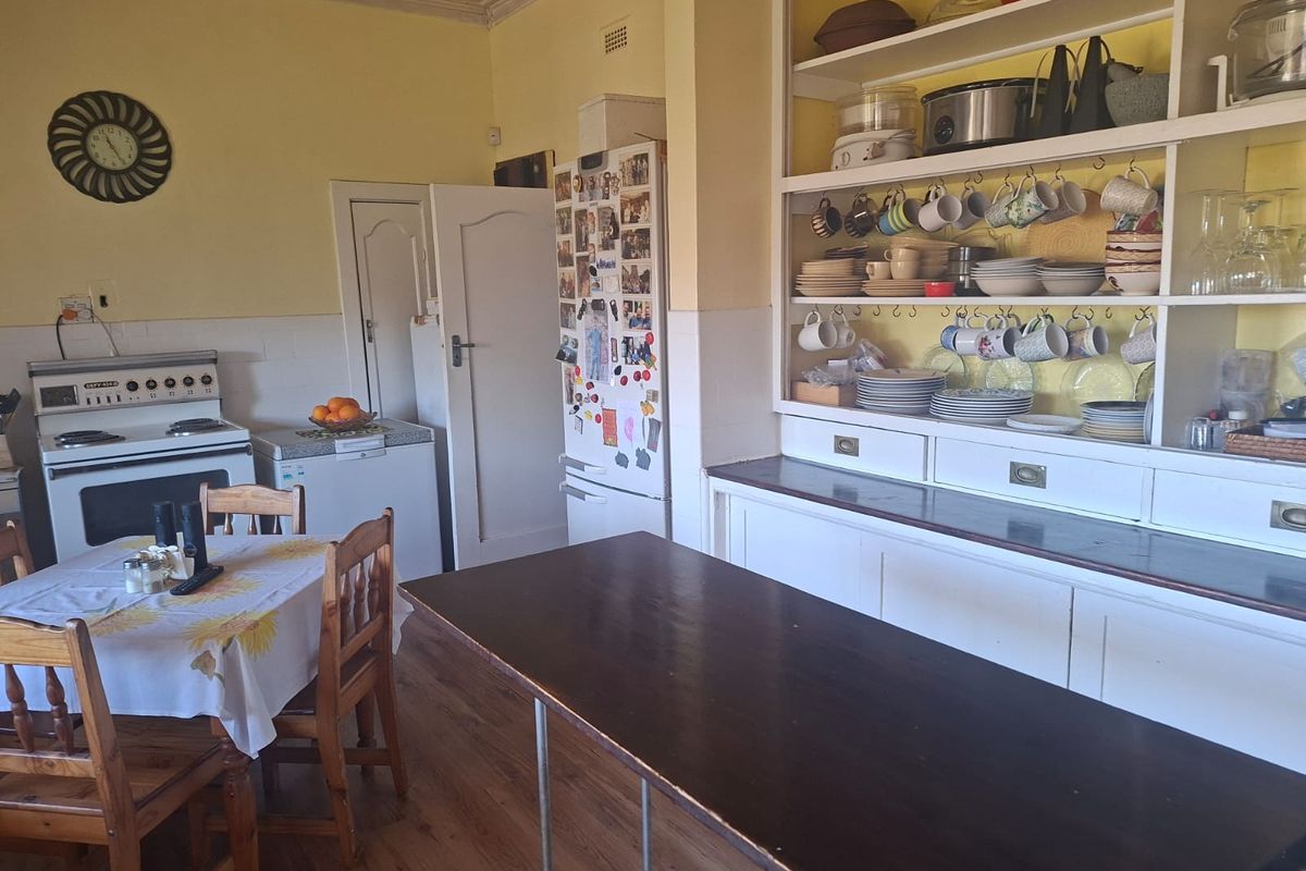 A dated kitchen featuring a freestanding stove, built-in open shelving, and laminate flooring, offering significant potential for a modern renovation.