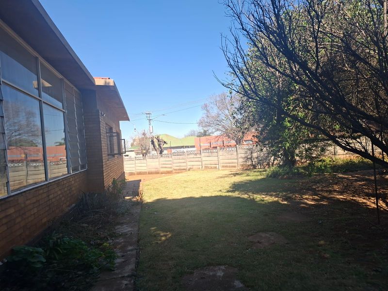 A view of the rear garden featuring a brick exterior wall, louvre windows, and a precast concrete boundary wall.