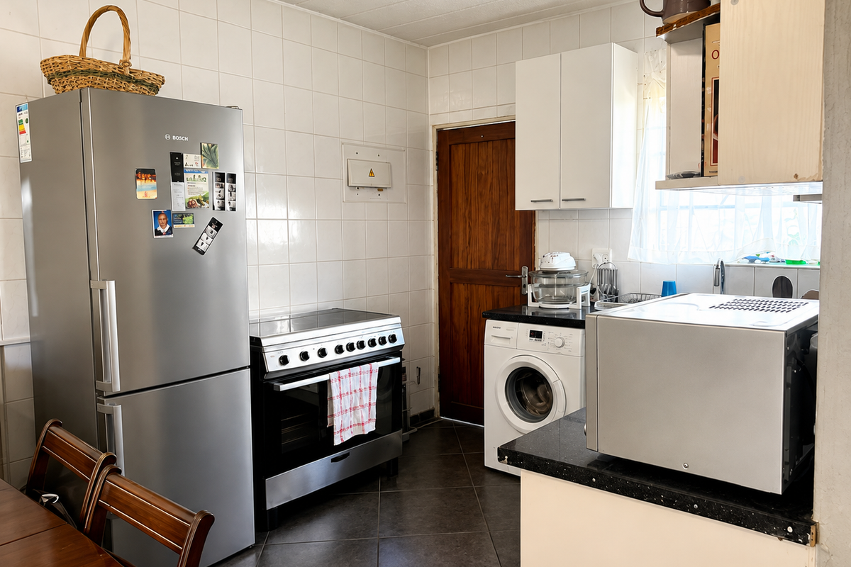 A functional kitchen featuring tiled walls, dark tiled flooring, black granite countertops, and built-in cabinetry with space for a washing machine and oven.