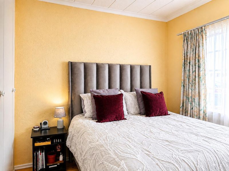 A cozy bedroom featuring textured yellow walls, a coved ceiling, and a built-in cupboard, providing a functional and comfortable sleeping space.