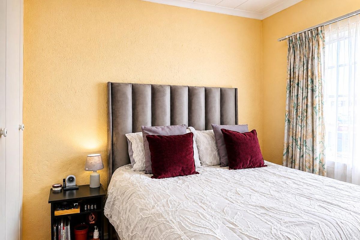 A cozy bedroom featuring textured yellow walls, a coved ceiling, and a built-in cupboard, providing a functional and comfortable sleeping space.