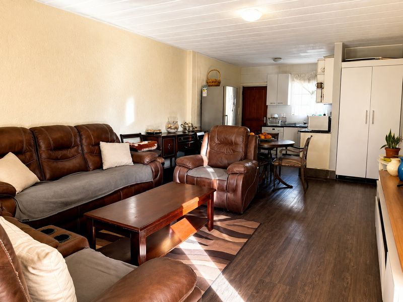 Open plan living and kitchen area featuring laminate flooring, functional cabinetry, and a neutral color palette, offering a practical and connected living space.