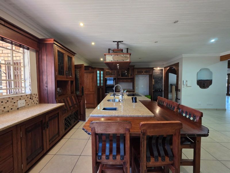 Spacious kitchen featuring extensive wooden cabinetry, a large central island with granite countertops, integrated appliances, and tiled flooring.