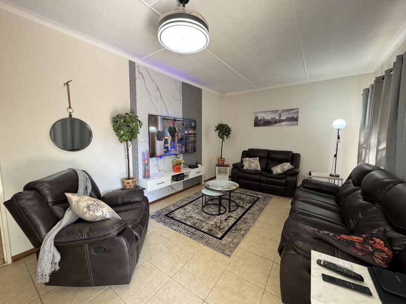 A comfortable living room featuring tiled flooring, a modern feature wall with a mounted television, and a floating media console.