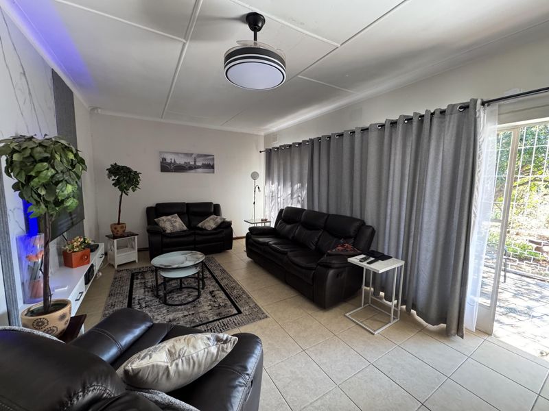 A comfortable living room featuring tiled flooring, a modern ceiling fan, and a large sliding glass door providing access to the outdoor area.