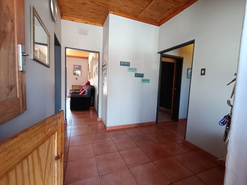 A functional hallway featuring terracotta-style floor tiles and a warm timber-paneled ceiling, providing access to adjacent living and bedroom areas.
