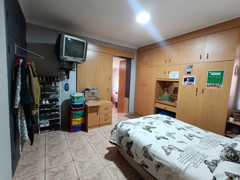 A bedroom featuring extensive built-in wooden cabinetry and tiled flooring, offering functional storage space with potential for modern cosmetic updates.