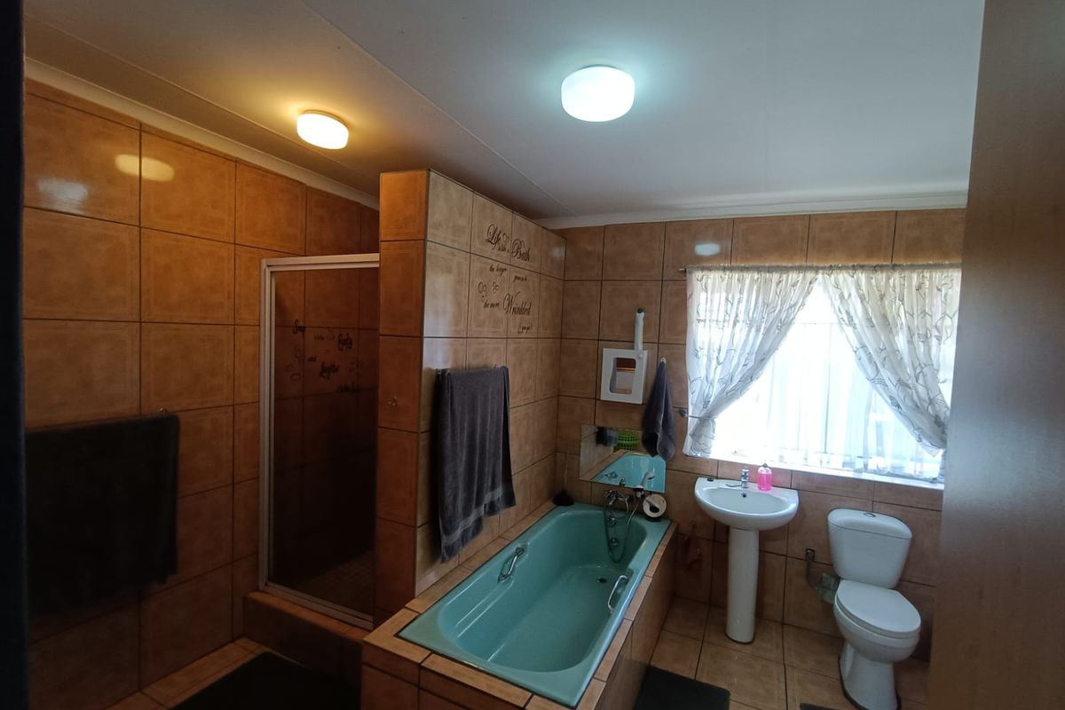 A functional bathroom featuring a built-in bathtub, separate shower enclosure, pedestal basin, and toilet, finished with full-height wall tiling.