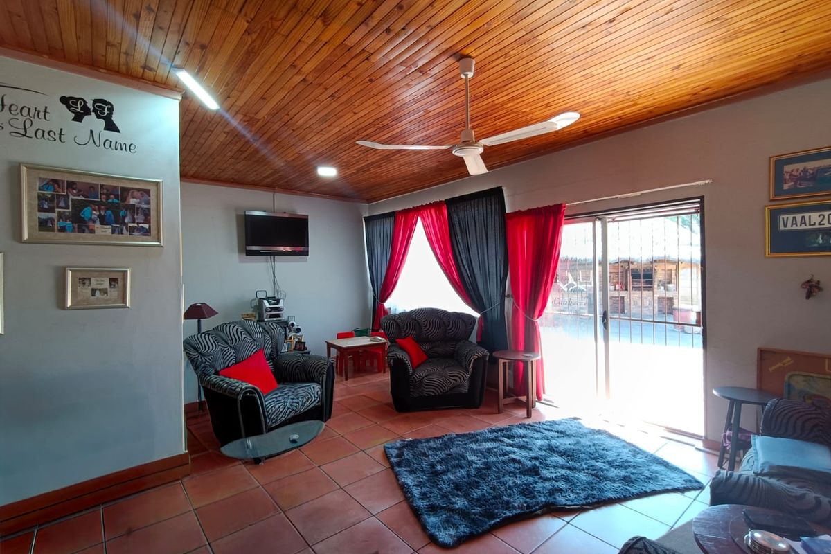 A living room featuring a timber-clad ceiling, ceiling fan, tiled flooring, and a sliding glass door providing access to the exterior.