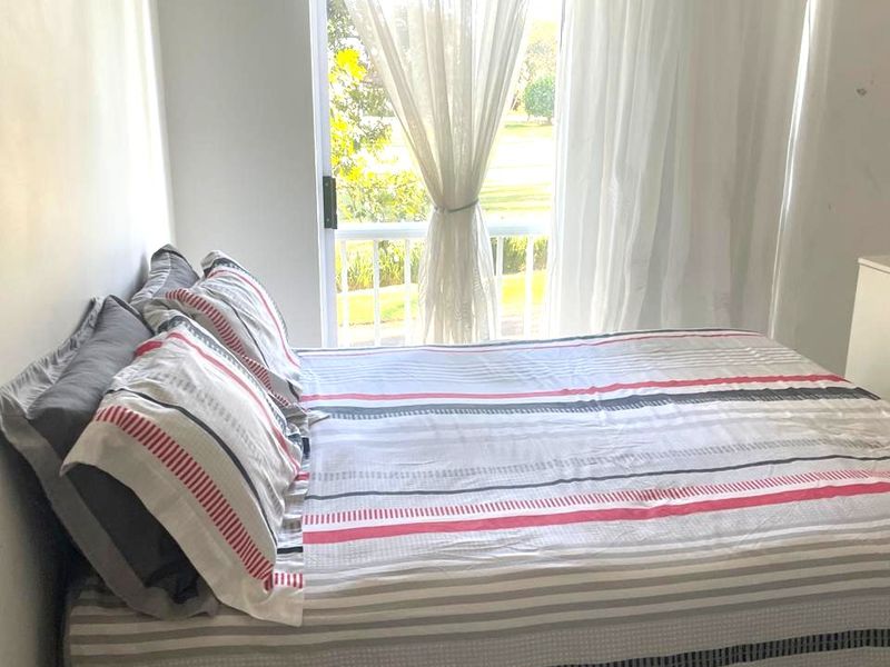 A bedroom featuring a sliding glass door that opens onto a balcony, providing natural light and outdoor access.