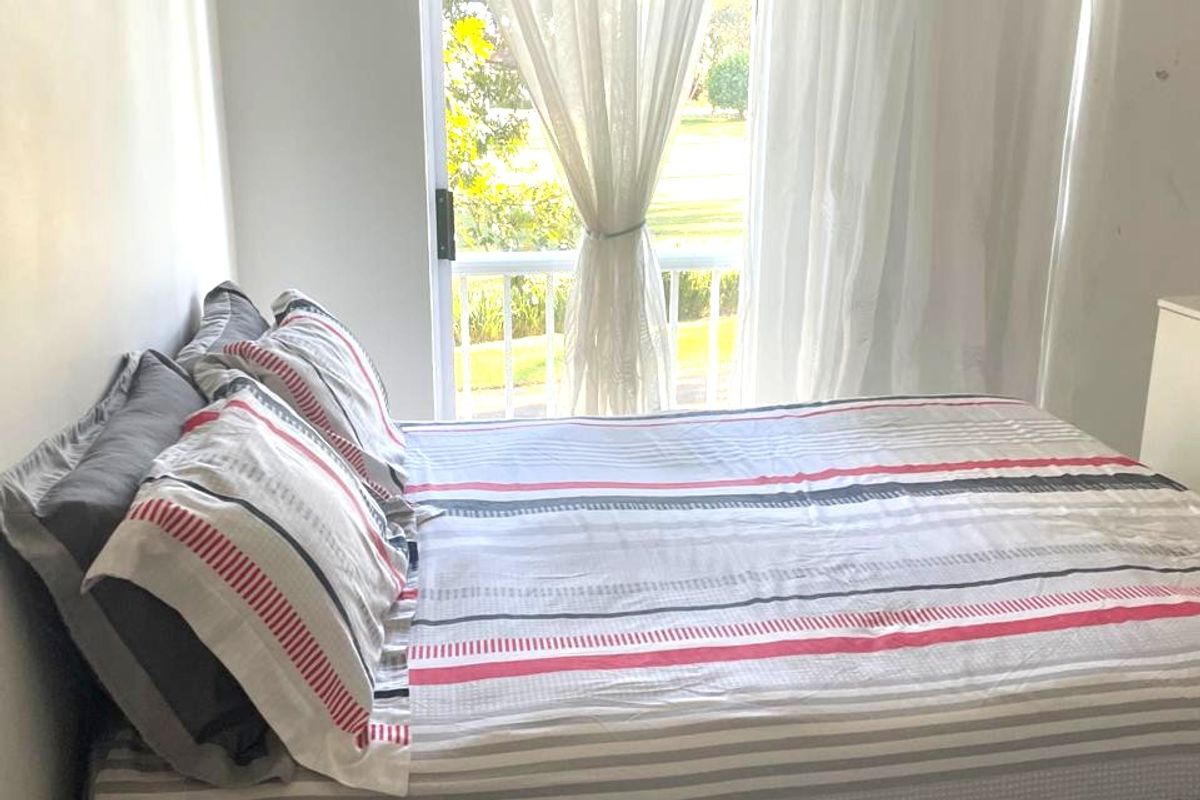 A bedroom featuring a sliding glass door that opens onto a balcony, providing natural light and outdoor access.