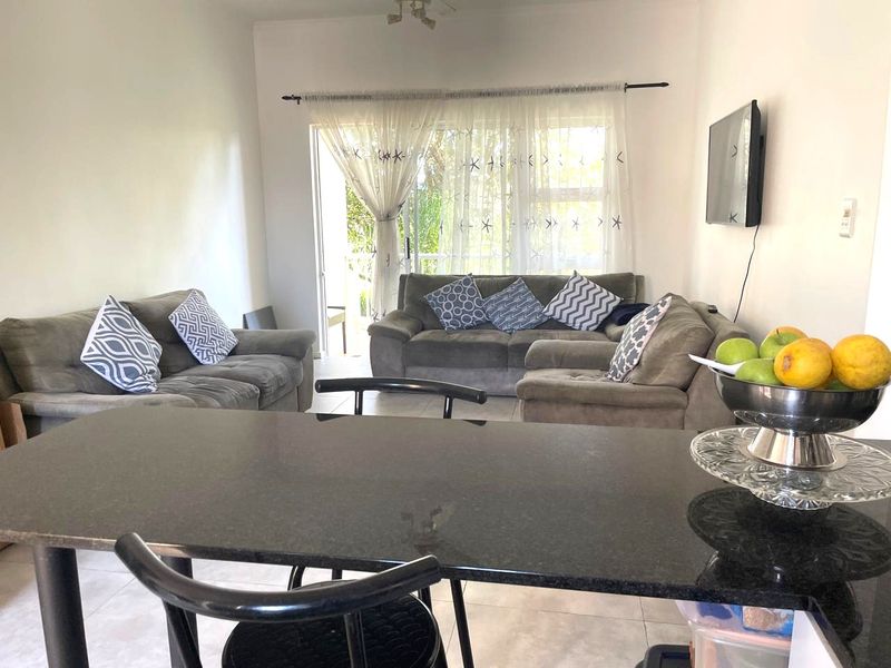 Open-plan living area featuring tiled flooring, a granite kitchen counter, and a sliding glass door leading to an outdoor space.