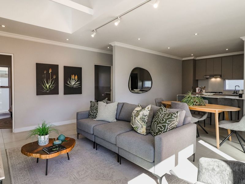 Modern open-plan living area featuring a contemporary kitchen with island, recessed lighting, and neutral tiled flooring, creating a bright and cohesive living space.