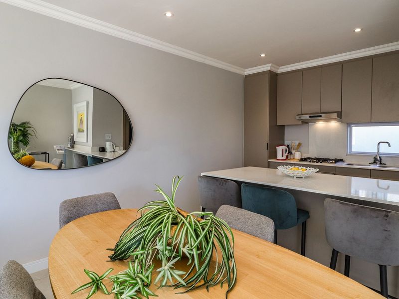 Modern open-plan kitchen featuring sleek cabinetry, stone countertops, integrated gas hob, and recessed lighting, seamlessly flowing into the dining area.