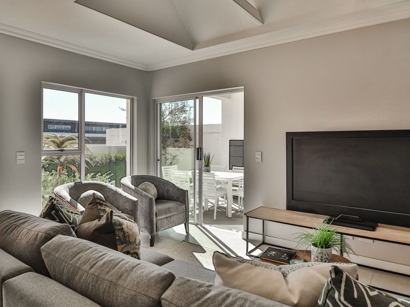 Bright living room featuring a tray ceiling, tiled flooring, and large sliding glass doors providing seamless access to the outdoor patio area.