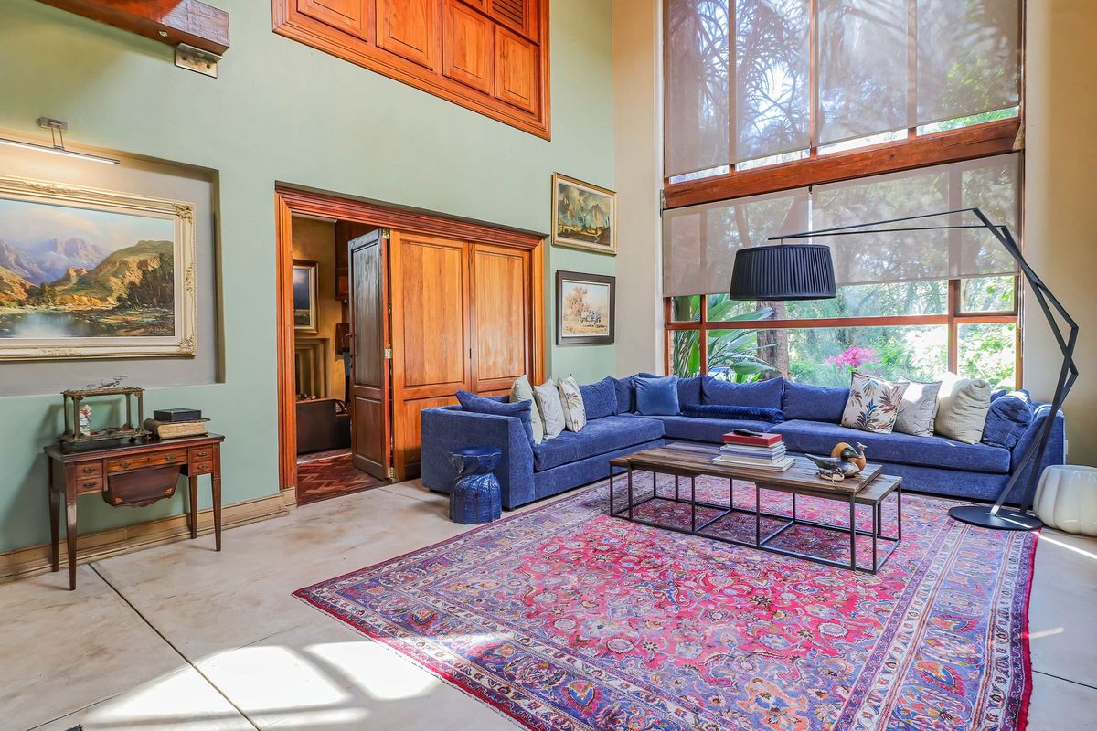 Spacious double-volume living room featuring polished concrete floors, large windows with natural light, and elegant wooden architectural details.