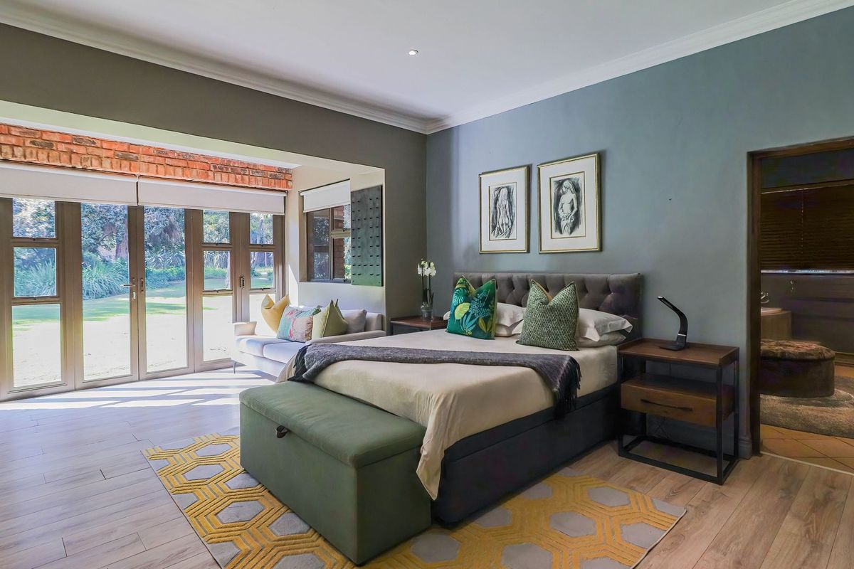 Spacious bedroom featuring laminate flooring, recessed lighting, and large folding glass doors providing direct access to the garden.