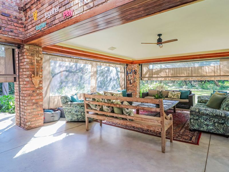 Spacious covered patio featuring exposed brick walls, concrete flooring, and a ceiling fan, seamlessly connecting indoor and outdoor living areas.