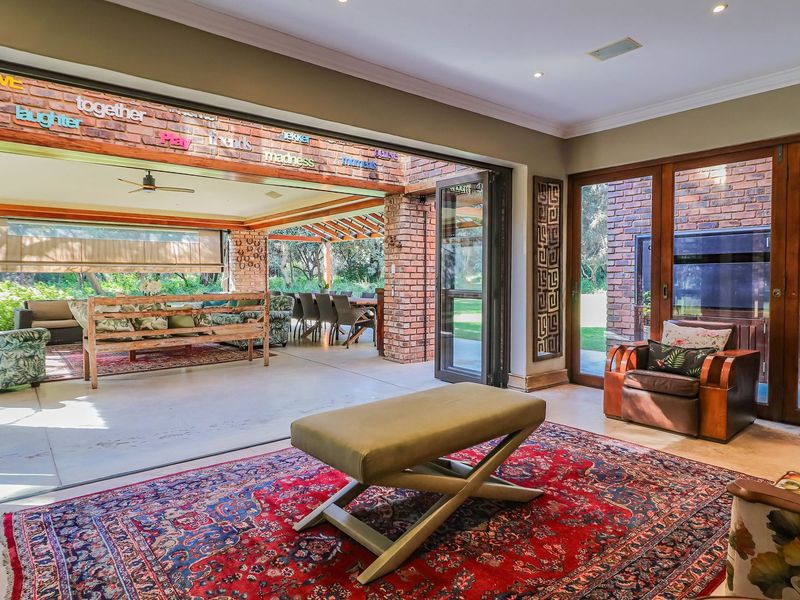 Spacious open-plan living area featuring large stacking glass doors that seamlessly connect the interior to a covered outdoor patio and garden.