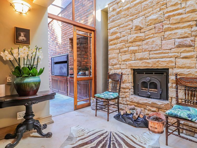 A cozy living area featuring a prominent natural stone wall with a built-in fireplace and direct access to an outdoor patio space.
