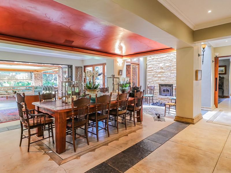 Spacious open-plan living and dining area featuring a stone fireplace, wood-burning stove, and large bi-fold doors opening to an outdoor patio.