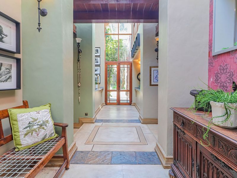 Spacious entrance hall featuring double-height ceilings, exposed timber beams, and elegant tiled flooring leading to a grand glass-paneled entrance.